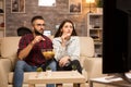 Beautiful young couple looking worried at tv while watching a movie Royalty Free Stock Photo