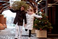 Beautiful young couple in love buying a Christmas tree from the market to decorate their home. Caucasian man and woman Royalty Free Stock Photo