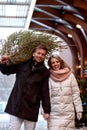 Beautiful young couple in love buying a Christmas tree from the market to decorate their home. Caucasian man and woman Royalty Free Stock Photo