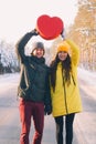 Couple in love holding a big red heart on the background of winter snowy forest Royalty Free Stock Photo