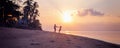 Beautiful young couple in love whirls holding hands on the beach at sunset during the honeymoon vacation travel Royalty Free Stock Photo