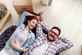 Beautiful young couple lying on the floor among cardboard boxes in their new apartment they just moved in