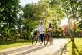 Beautiful young couple man and woman ride bicycles on the alley in the park and communicate. Woman and man pull a bike through the Royalty Free Stock Photo