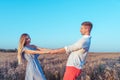 Beautiful and young couple man and woman, summer wheat field, holding each other`s hands. Having fun playing happy Royalty Free Stock Photo