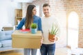 Beautiful young couple moving to a new house, smiling happy holding cardboard boxes at new apartment Royalty Free Stock Photo