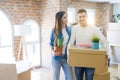 Beautiful young couple moving to a new house, smiling happy holding cardboard boxes at new apartment Royalty Free Stock Photo