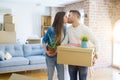 Beautiful young couple moving to a new house, smiling happy holding cardboard boxes at new apartment Royalty Free Stock Photo