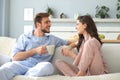 Beautiful young couple in pajamas is looking at each other and smiling on a sofa in the living room Royalty Free Stock Photo