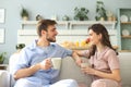 Beautiful young couple in pajamas is looking at each other and smiling on a sofa in the living room Royalty Free Stock Photo