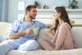 Beautiful young couple in pajamas is looking at each other and smiling on a sofa in the living room Royalty Free Stock Photo