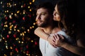 Beautiful young couple in pajamas on nicely decorated Christmas tree background. Royalty Free Stock Photo