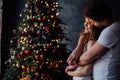 Beautiful young couple in pajamas on nicely decorated Christmas tree background. Royalty Free Stock Photo