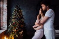 Beautiful young couple in pajamas on nicely decorated Christmas tree background. Royalty Free Stock Photo