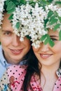 Beautiful young couple posing and smiling under white flowers in spring garden. Portraits of happy family embracing at blooming Royalty Free Stock Photo