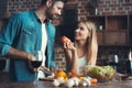 Beautiful young couple preparing a healthy meal together while spending free time at home.