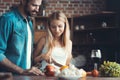 Beautiful young couple preparing a healthy meal together while spending free time at home.