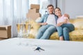 beautiful young couple relaxing on couch while moving into new home with champagne glasses and keys