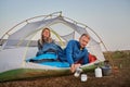 Beautiful young couple resting in camp tent and drinking tea. Royalty Free Stock Photo