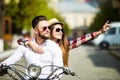 Beautiful young couple riding scooter together while happy woman pointing away and smiling Royalty Free Stock Photo