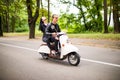 Beautiful young couple riding scooter together, woman hugging her boyfriend. Side view on speed. Royalty Free Stock Photo