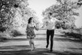 Beautiful young couple running holding hands in spring meadow. Happy stylish family having fun on road at field trees. Romantic Royalty Free Stock Photo