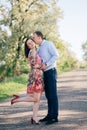 Beautiful young couple sensual hugging and kissing on road in sunshine among spring field and trees. Happy family in love Royalty Free Stock Photo
