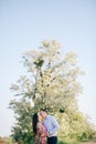 Beautiful young couple sensual hugging and kissing on road in sunshine among spring field and trees. Happy family in love Royalty Free Stock Photo