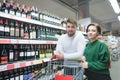 Beautiful young couple shopping bag in a supermarket in the alcohol department on the background of wine Royalty Free Stock Photo