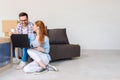 Beautiful young couple shopping on-line using a laptop computer and smiling while sitting in their new apartment after move Royalty Free Stock Photo