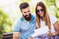 Young couple sitting on a bench in the park, they are reading some documentation Royalty Free Stock Photo