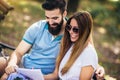 Young couple sitting on a bench in the park, they are reading some documentation Royalty Free Stock Photo