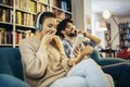 Young couple sitting in the cafe, drinking coffee and listening to music with smart phone Royalty Free Stock Photo