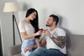 A beautiful young couple sitting on the couch and drinking wine, they are happy together Royalty Free Stock Photo