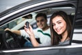 Beautiful young couple sitting at the front seats of their new car while woman showing keys and smiling Royalty Free Stock Photo