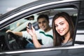 Beautiful young couple sitting at the front seats of their new car while woman showing keys and smiling Royalty Free Stock Photo