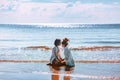 Beautiful young couple sitting on sand in front of each other in sea waves. Young man and woman love story on the beach Royalty Free Stock Photo