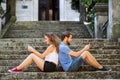 Young couple with smartphones sitting on stairs in town. Royalty Free Stock Photo