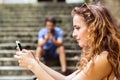 Young couple with smartphones sitting on stairs in town. Royalty Free Stock Photo