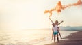 Beautiful young couple with smoke bomb on the beach