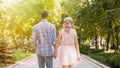 Beautiful young couple strolling through sunlit bright green park, romantic date