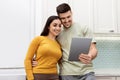 Beautiful young couple taking photo on digital tablet at kitchen Royalty Free Stock Photo