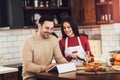 Young couple is using a digital tablet and smiling while cooking in kitchen at home Royalty Free Stock Photo