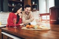 Young couple is using a digital tablet and smiling while cooking in kitchen at home Royalty Free Stock Photo