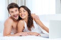 Beautiful young couple using laptop and looking at camera Royalty Free Stock Photo