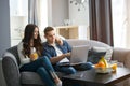 Beautiful young couple using laptop while sitting on the couch together at home. Royalty Free Stock Photo