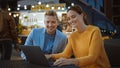 Beautiful Young Couple is Using a Laptop while Sitting at a Table in an Outdoors Street Food Cafe. Royalty Free Stock Photo