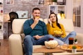 Beautiful young couple watching TV and eating fast food takeaway Royalty Free Stock Photo