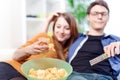 Beautiful young couple watching tv and eating on a sofa Royalty Free Stock Photo