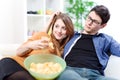 Beautiful young couple watching tv and eating on a sofa Royalty Free Stock Photo