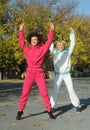 Beautiful young curly hair woman in pink sportswear and middle age 50s woman doing sports outdoors. Royalty Free Stock Photo